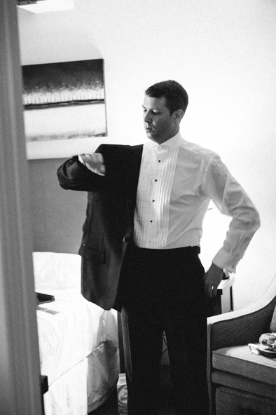 groom putting on tuxedo